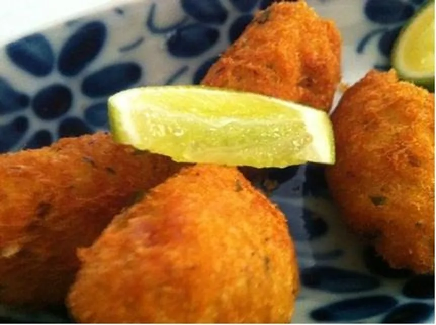 Bolinhos de bacalhau com limão servidos em prato de louça azul e branca do Ora Pois